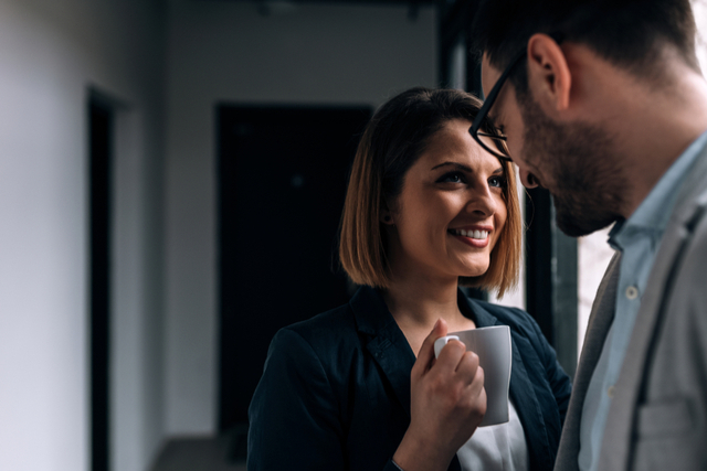 office romance, woman looks at man over a coffee cup